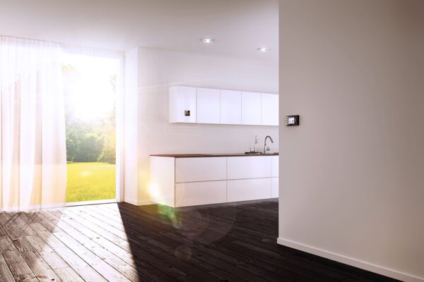A Wolf wall-mounted gas condensing boiler installed inside a white kitchen cupboard with a wall thermostat in a bright modern kitchen