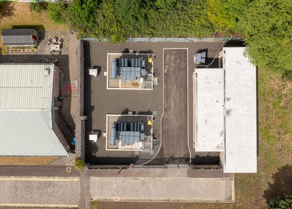 An aerial view of an electricity substation site with transformers and buildings surrounded by trees