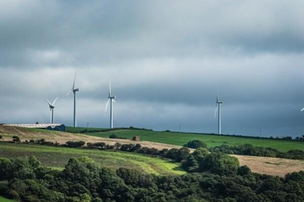 Wind turbines on a green hillside under a cloudy sky