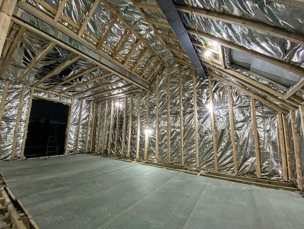A loft conversion interior lined with reflective multifoil insulation stapled between timber studs and rafters