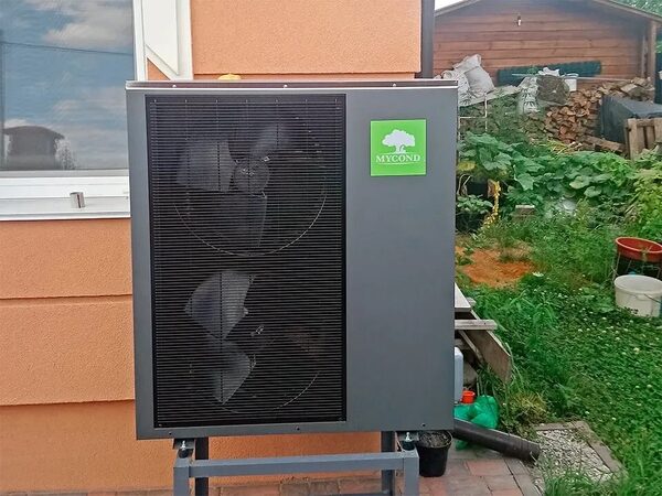 A Mycond air source heat pump unit installed outside a house in a garden