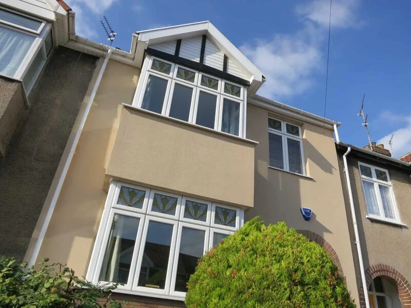 The front of an Edwardian terraced house with smooth beige external solid-wall insulation render and white uPVC windows