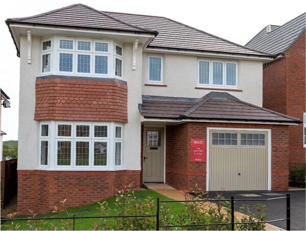 A modern two-storey detached brick and render house with a SOLD sign by the front door and an integral garage