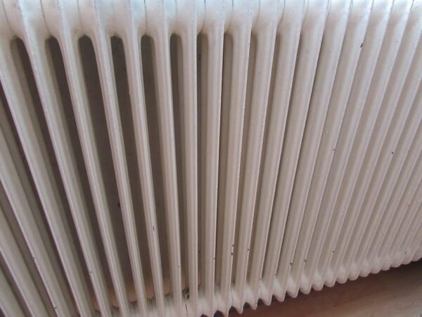 A close-up of a white column radiator installed in a home