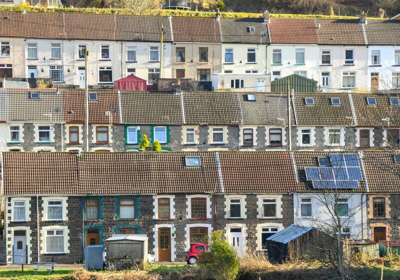 Rows of Welsh terraced houses on a hillside, one roof fitted with solar panels