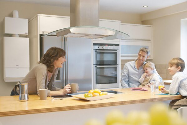 A family in a modern kitchen with a wall-mounted white combi boiler visible on the left