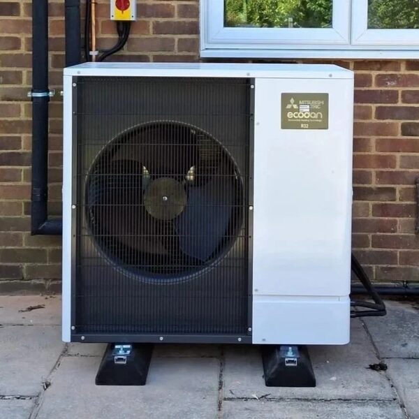 A Mitsubishi Ecodan air source heat pump unit installed outside a brick house.