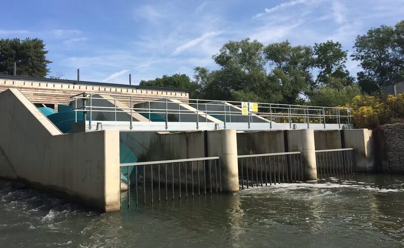 A community hydroelectric scheme with Archimedes screw turbines installed on a river weir next to a wooden building