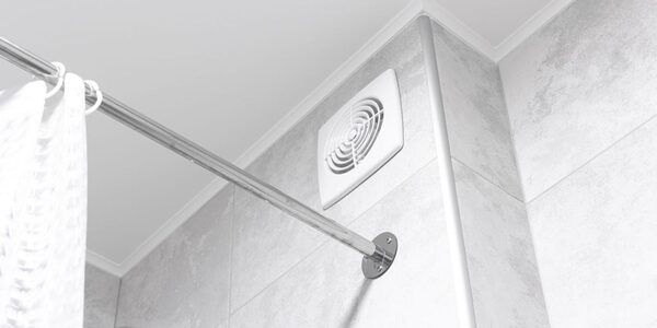 A white bathroom extractor fan mounted on a tiled wall next to a shower curtain rail