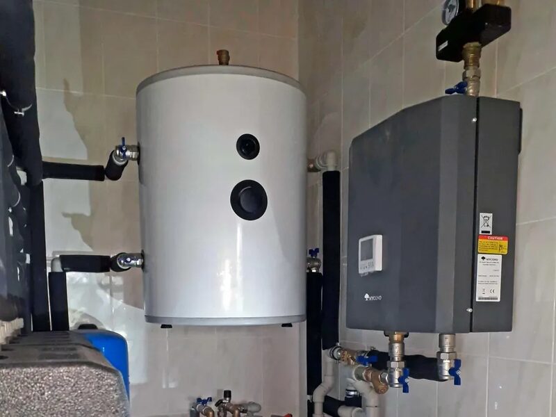 A wall-mounted white hot water cylinder and a grey Mycond heating unit with pipework and valves installed in a tiled utility room