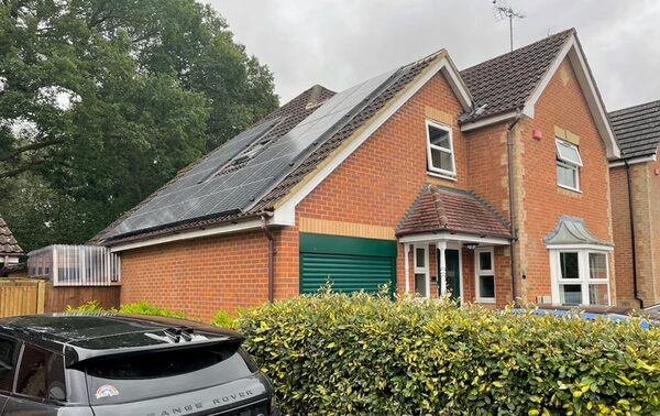 A brick UK house with solar panels on the roof under an overcast sky