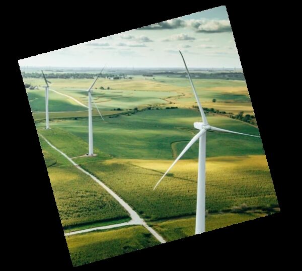 Wind turbines standing in green farmland under a partly cloudy sky