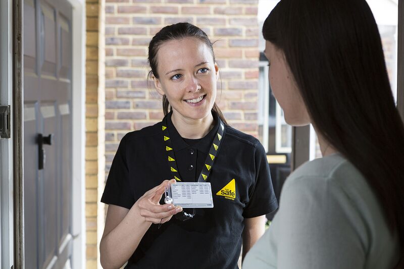 A Gas Safe registered engineer showing her ID card to a householder at the door