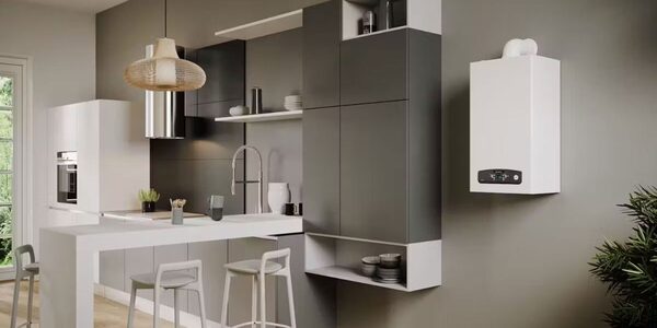A white wall-mounted Ariston combi boiler installed on the wall of a modern grey and white kitchen