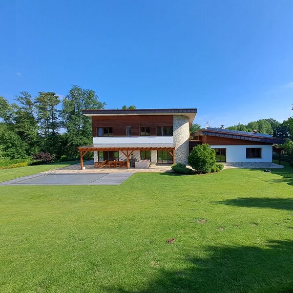 A modern house with solar panels on the roof, seen from a large lawn