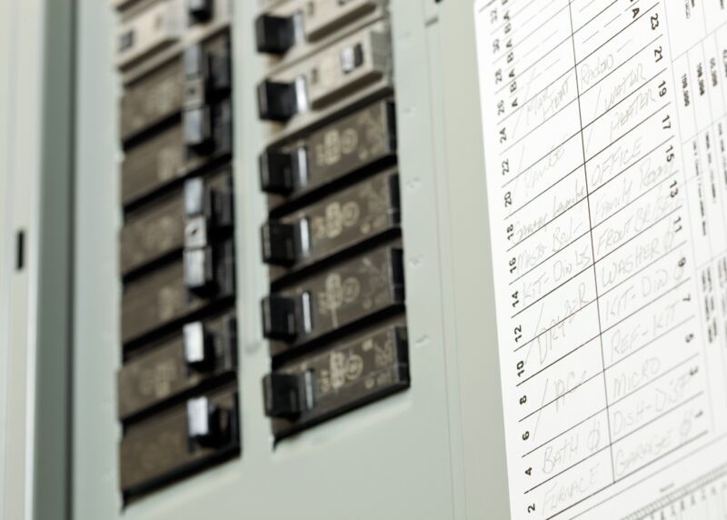 A close-up of a domestic consumer unit with circuit breakers and a handwritten circuit directory label