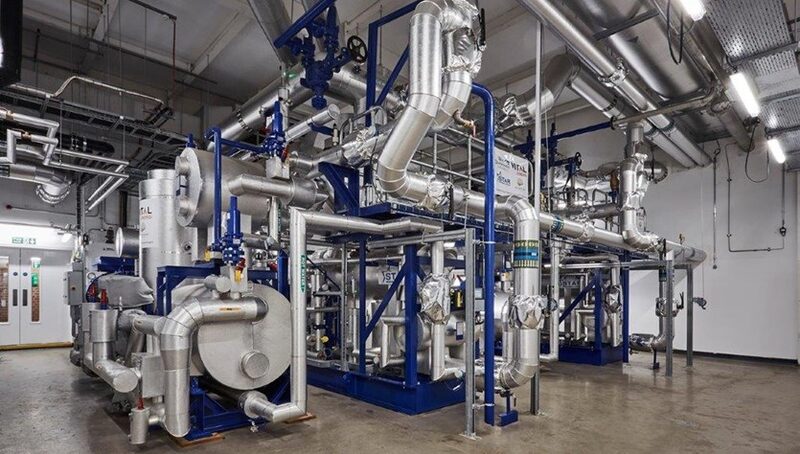 An industrial energy centre plant room with insulated pipework, pumps and heat network equipment
