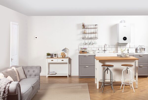 A white wall-mounted gas combi boiler installed in a bright open-plan kitchen and living room