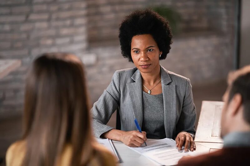 An adviser in a grey blazer going over paperwork with a couple at a table