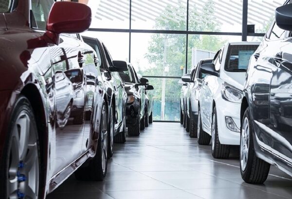 Rows of new cars parked in a bright car dealership showroom
