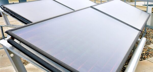 Flat-plate solar thermal collector panels mounted on a metal frame on a flat roof