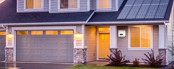 A house at dusk with rooftop solar panels and a SofarSolar battery/inverter unit mounted on the exterior wall