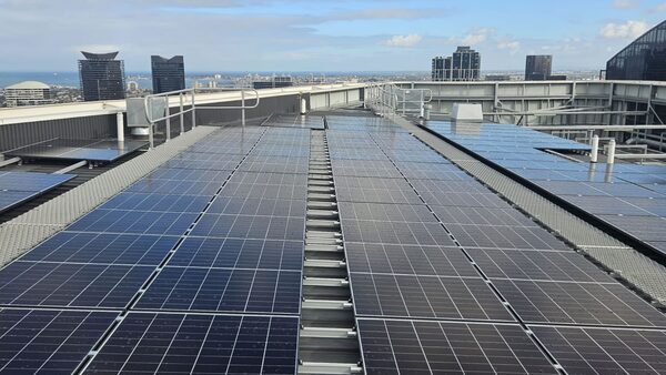 Rows of solar panels installed on the flat rooftop of a high-rise building with a city skyline in the background