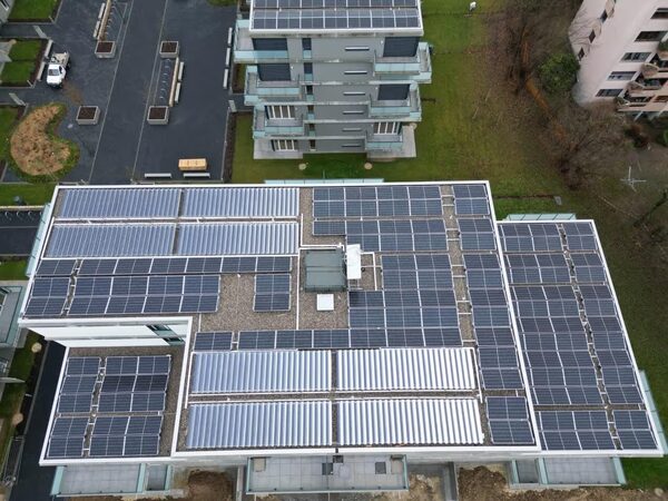 Aerial view of a flat apartment-block roof covered with solar PV panels and solar thermal collectors