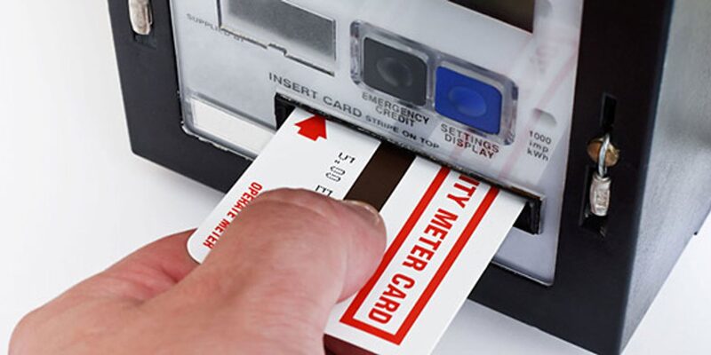A hand inserting an electricity meter card into a prepayment electricity meter