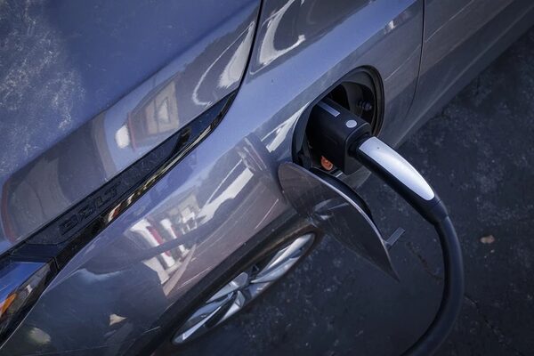 A grey electric car plugged in with a charging cable at its charging port