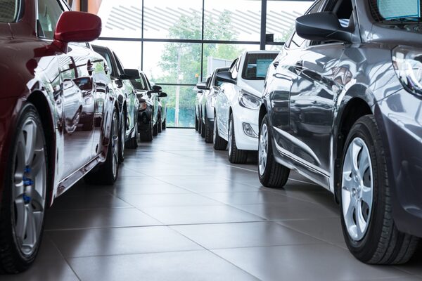 Rows of new cars parked in a bright car dealership showroom