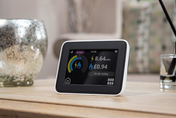 A smart meter in-home display on a wooden table showing energy usage of 8.64 kWh and £0.94 so far today
