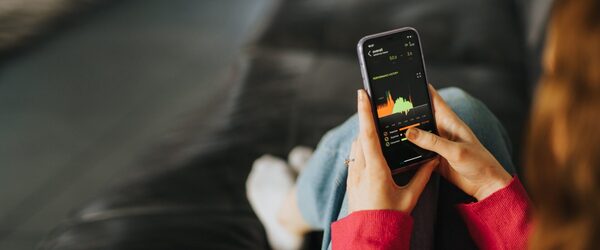 A person holding a smartphone displaying an energy monitoring app with a usage graph