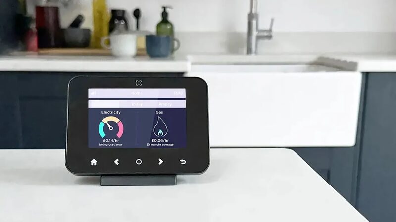 A smart energy monitor display on a kitchen counter showing live electricity and gas costs