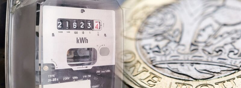 A close-up of an electricity meter display next to a one pound coin