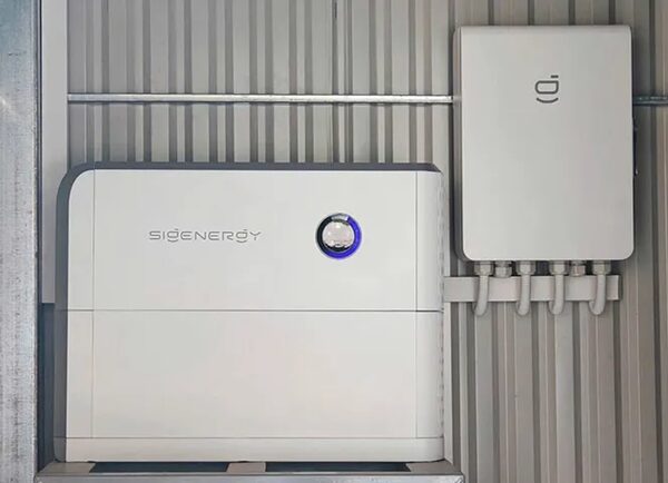 A Sigenergy home battery unit and matching inverter mounted on a corrugated metal wall