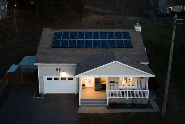 A bungalow-style house at dusk with a rooftop solar panel array, seen from above
