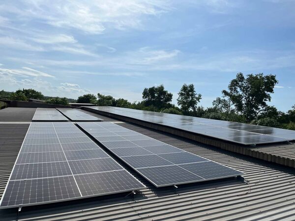 Rows of solar panels installed on a corrugated metal roof under a blue sky