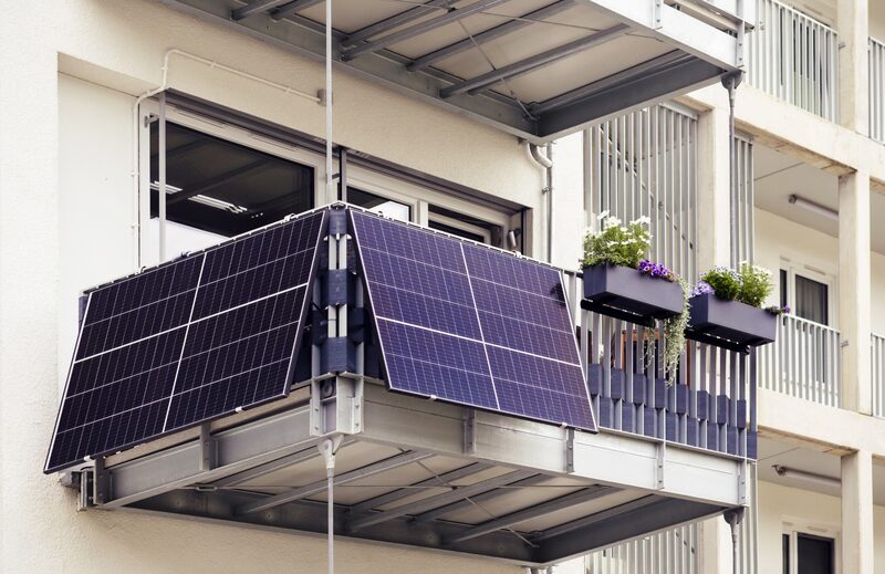 Two plug-in solar panels mounted on the railing of a small apartment balcony