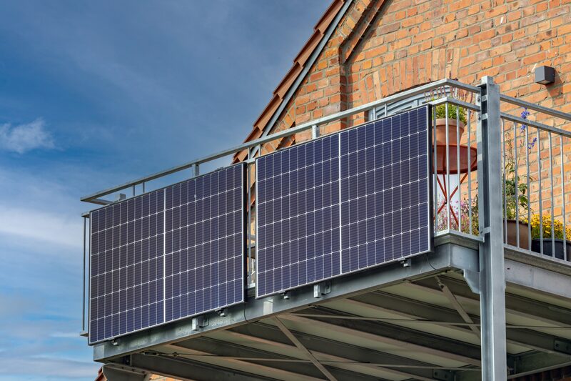 Solar panels mounted on a balcony railing of a brick house