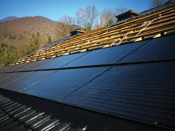 Solar panels being installed on a tiled roof with battens exposed, hills in the background
