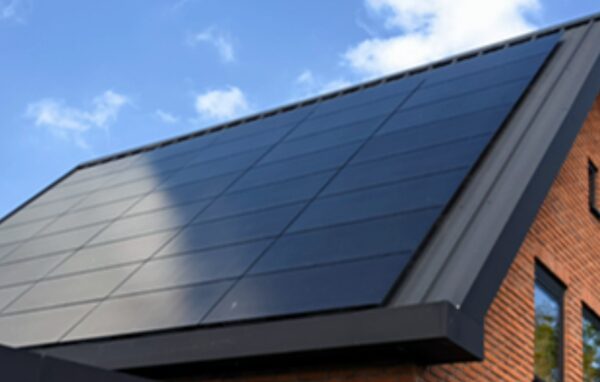Solar panels fitted flush on the sloped roof of a brick house under a blue sky