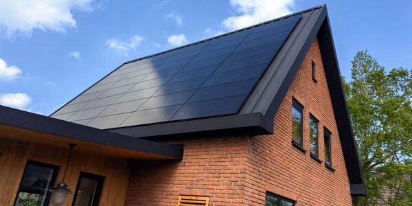 Black solar panels fitted on the pitched roof of a modern brick house