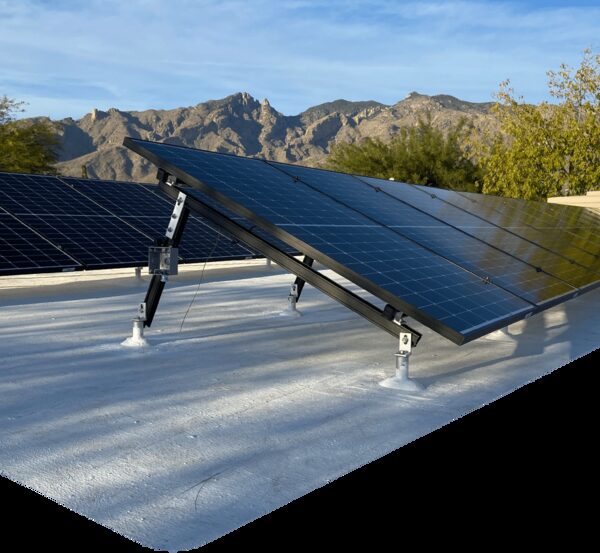 Tilted solar panels mounted on ballasted frames on a flat roof with mountains behind