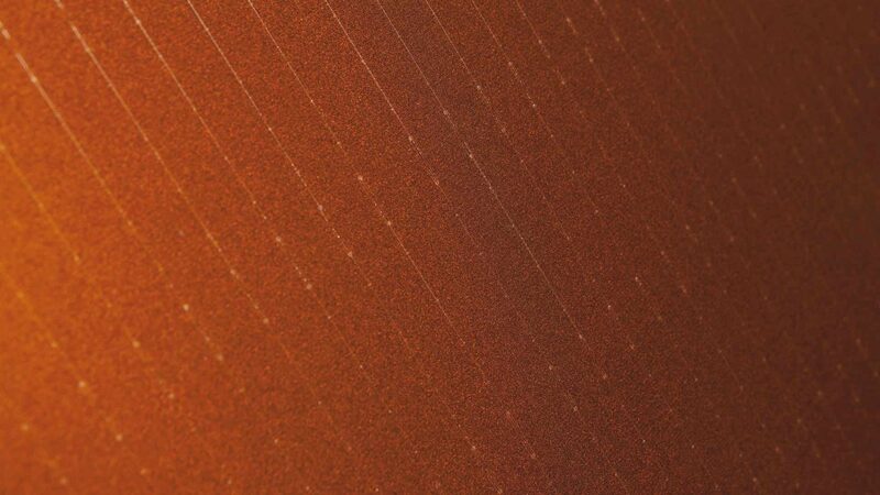 A close-up of the orange textured surface of a FuturaSun Silk Pro Orange solar panel with faint diagonal cell lines