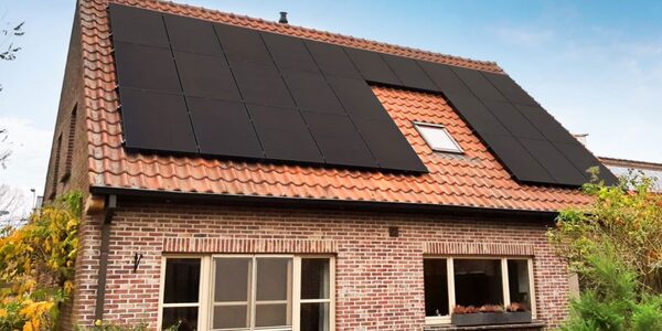 A brick house with black solar panels fitted on its tiled roof