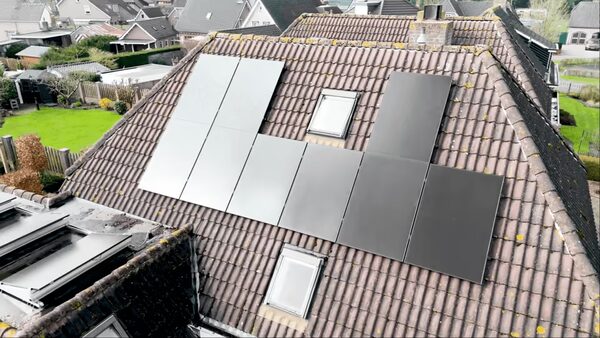 Aerial view of dark solar panels installed on the tiled roof of a suburban house