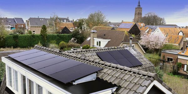 Black solar panels installed on the tiled roof of a house in a residential neighbourhood