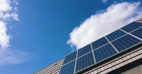 Solar panels installed on a tiled roof against a blue sky with clouds