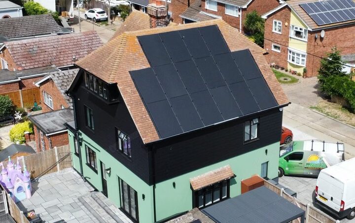 Aerial view of a UK house with a large array of black solar panels on its tiled roof